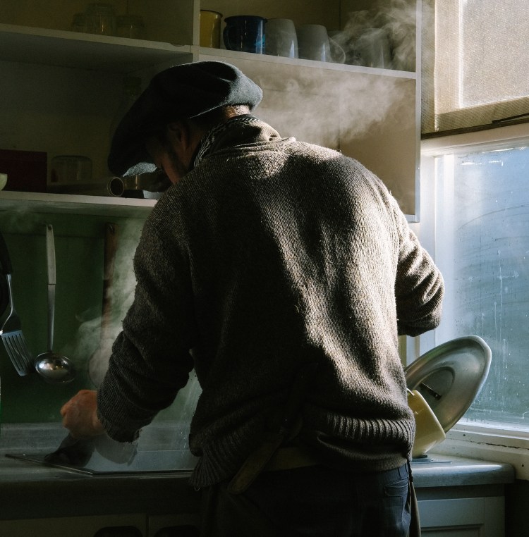 A gaucho man doing the dishes in a mountain hut in Patagonia.